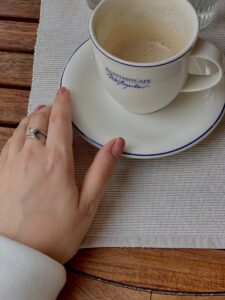 A person's hand holding a coffee cup and a ring