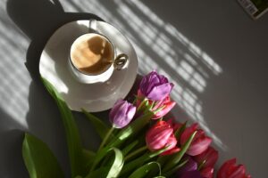 A cup of coffee and some tulips on a table